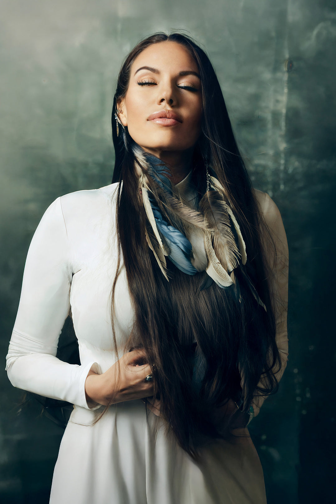 Beckah Shae wearing long natural feather earrings featuring earthy tones of emerald, chestnut, and ivory.