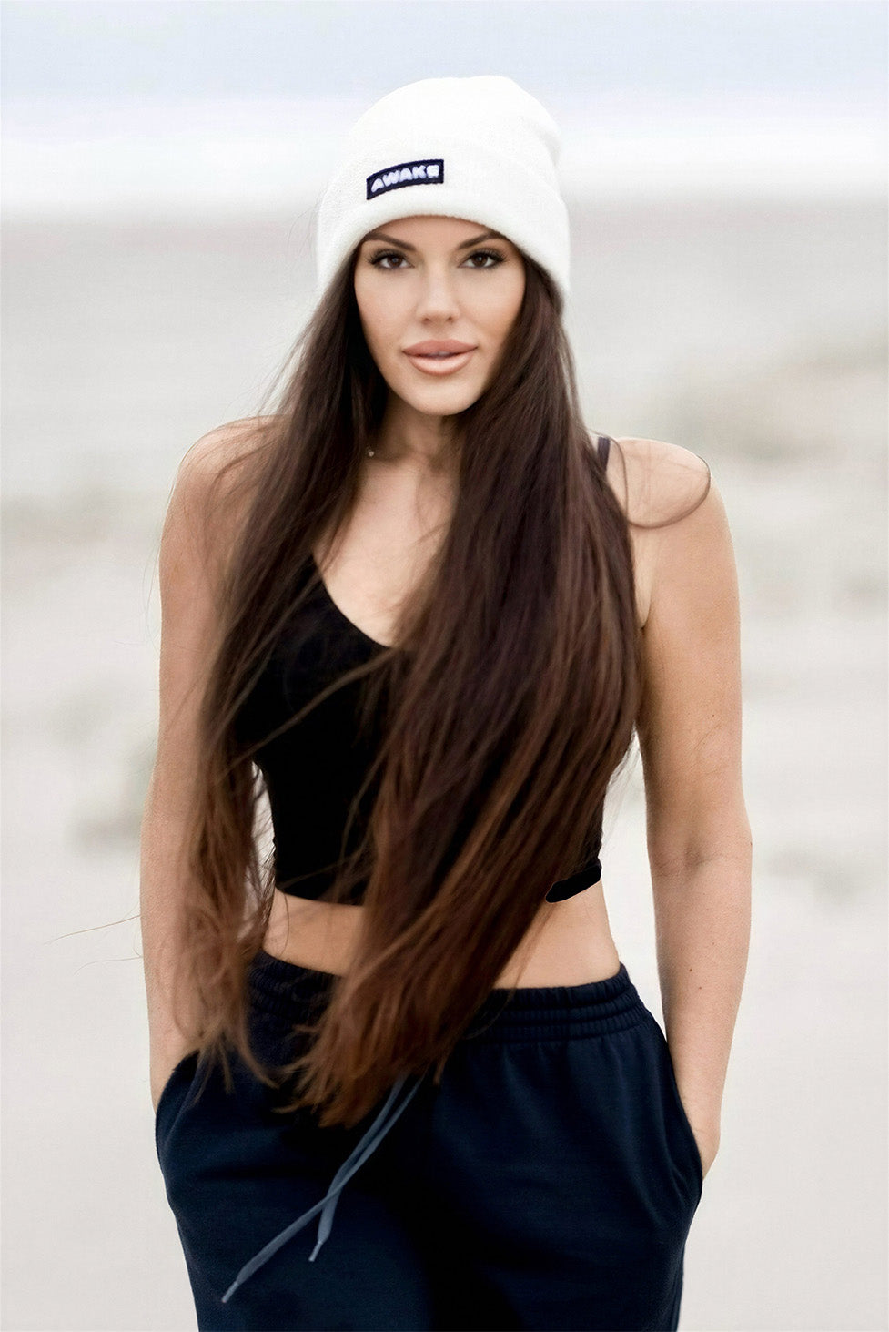 Beckah Shae wearing a white awake beanie and black outfit against a light background